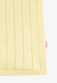 Tissu tricoté côtelé jaune clair avec des rayures texturées verticales et une petite étiquette en tissu beige sur le bord droit.
