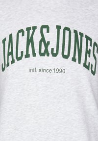 Szary sweatshirt z wyrazistym zielonym napisem "JACK & JONES" oraz "intl. since 1990" poniżej. Wykonany z bawełnianego materiału o miękkiej fakturze.
