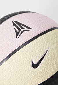 Multicolored basketball with textured surface, featuring pink, black, and cream sections. Black logo accents prominently displayed.