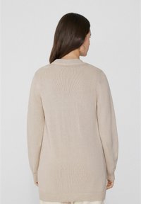 Beige Langarm-Pullover mit gestrickter Textur, Rundhalsausschnitt und gerippten Ärmeln. Schlichte Designs, ideal zum Layering.