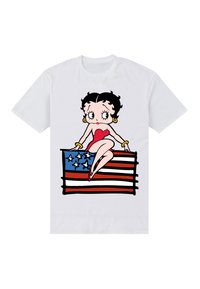 Hvid t-shirt med en illustreret karakter med sort hår, rød kjole og guldøreringe, siddende på et design af en rød og blå stribet flag.
