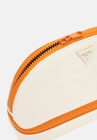 Hvid lynl�åspose med tekstureret overflade og lyselement orange lynlås. Har et trekantet logo i guld på siden. Rundet form.