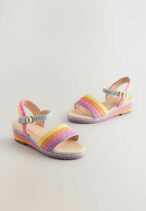 Sandały na koturnie z wielokolorowymi plecionymi paskami w odcieniach różu, żółci i niebieskiego, z klamrą na kostce i jasnobeżową podeszwą.