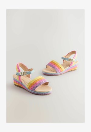 Kampaniniai batai su daugiaspalvėmis pinto dirželiais rožinės, geltonos ir mėlynos spalvų, turintys sagtį ant kulkšnies ir šviesiai béžinį padą.