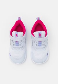 Zapatillas de bebé Nike en blanco y lavanda con forro interior acolchado rosa y correas de Velcro, vistas desde arriba sobre un fondo blanco.