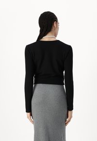 Zwarte langemouwen top met een ronde hals, gecombineerd met een aansluitende grijze ribgebreide rok. Soepele stofstructuur met een gestroomlijnde silhouet.