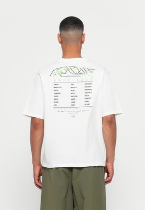 White short-sleeve t-shirt featuring green graphic text on the back with city names and logo. Relaxed fit, cotton material, plain design.