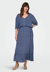 Tumši zila maxi kleita ar baltajiem punktiņiem, ar īsām piedurknēm, V-veida kakla izgriezumu, elastīgu jostasvietu un izplestu apakšmalu.