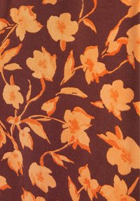 Motif floral orange avec des feuilles sur un fond de tissu marron foncé, montrant une texture lisse et des tiges fluides semblables à des vignes.