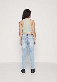 Lys grønn, tettsittende tanktopp kombinert med middels høye, falmede blå smale jeans. Jeansene har et klassisk fem-lommers design.