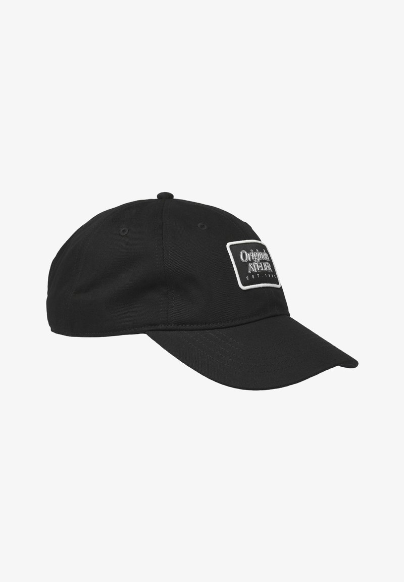 Casquette noire avec une visière courbée, présentant un patch rectangulaire blanc avec du texte. Fabriquée en tissu avec une texture lisse et une sangle réglable.