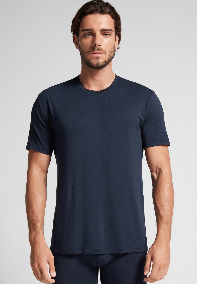 Granatowa koszulka z krótkim rękawem wykonana z miękkiego materiału, z okrągłym dekoltem i prostym wykończeniem, co zapewnia prosty, dopasowany wygląd.