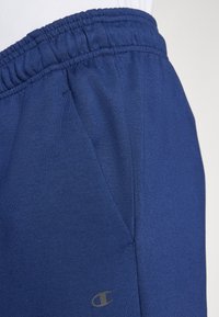 Navyblå träningsshorts i mjukt material, med resårmidja, sidofickor och en liten logo på nedre vänstra ben.