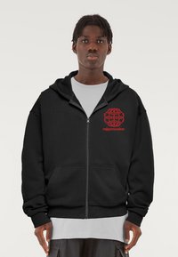 Fekete cipzáras kapucnis pulóver, pamutból készült, bal mellrészen egy nagy piros földgömb grafika és a "migonzales" felirat található. Két elülső zseb van.