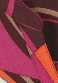 Tissu multicolore arborant de grands motifs géométriques en rose, orange et brun ; comprend des coutures visibles et un design propre et net.