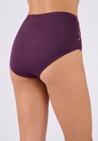 Parte inferior de bañador de cintura alta en púrpura profundo con bordado floral en el costado, textura suave y diseño de cobertura total.