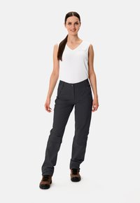 Pantaloni da trekking neri con vestibilità slim, realizzati in tessuto leggero, dotati di tasche e chiusura con bottone, abbinati a un top senza maniche bianco.