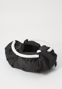 Borsa in tessuto nero con superficie testurizzata, decorata con piccoli fiori neri e manico in perle di agglomerato bianco.