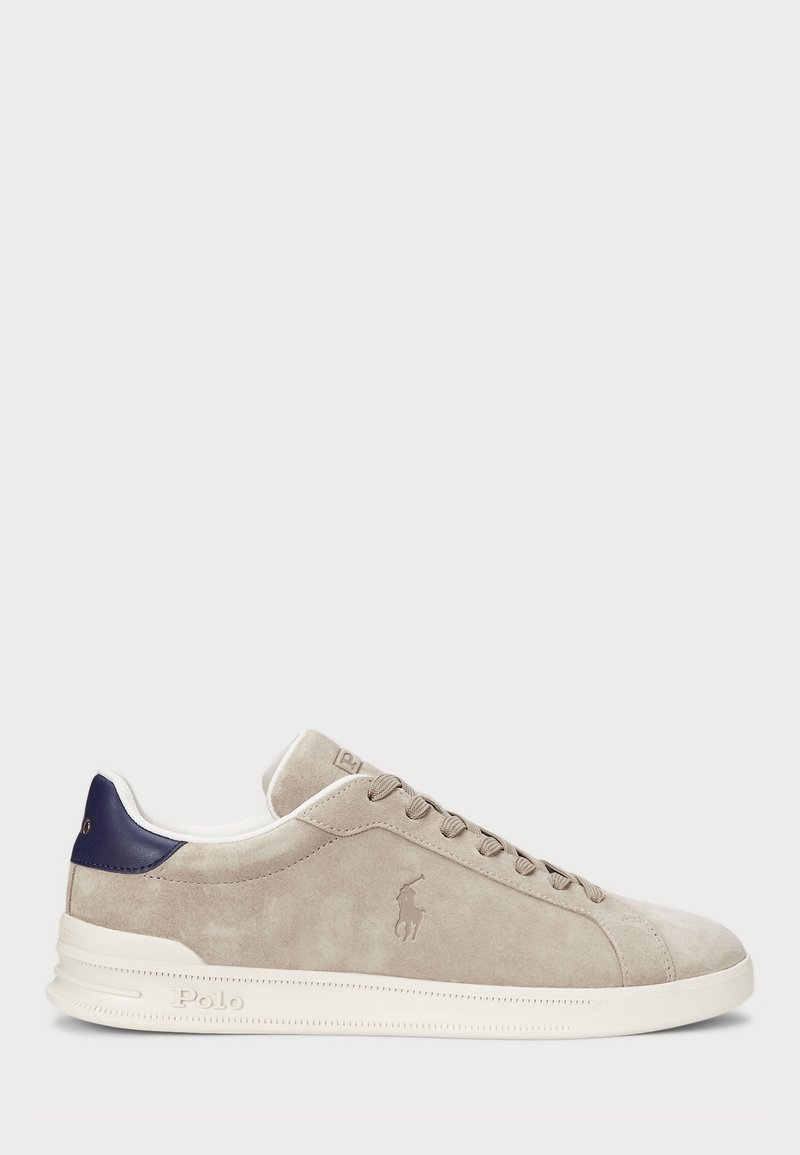 Baskets basses en daim beige avec languette de talon bleu marine, semelle blanche, lacets sur le devant et logo Polo embossé sur le côté et la semelle.