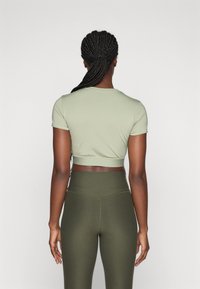 Oliivroheline lühikeste varrukatega crop top, kvaliteetsest siledast kangast, koos kõrge vöökohaga oliivroheline trikoo, millel on ühtlane disain.