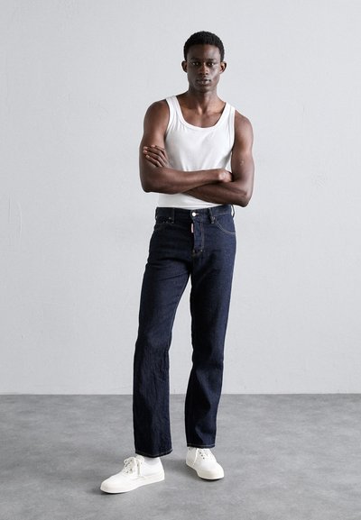 Dunkelblaue Denim-Jeans mit geradem Schnitt, kombiniert mit einem weißen Tanktop und weißen Sneakers, ausgestattet mit klassischem Fünf-Taschen-Design und verstellbarem Bund.