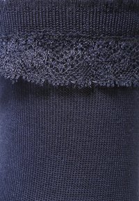Marineblaue gestrickte Socke mit Spitzenbesatz am oberen Rand. Der Hauptstoff ist glatt mit einer feinen, kleinen Textur.