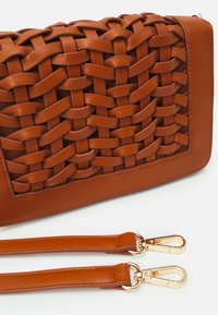 Bruine leren crossbodytas met geweven structuur, voorzien van een gladde afwerking, gouden hardware details en afneembare bandjes.