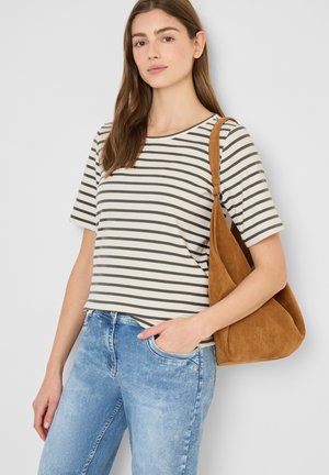 Ung kvinde iført en stribet kortærmet skjorte og lyseblå jeans, der bærer en brun skuldertaske i ruskind.