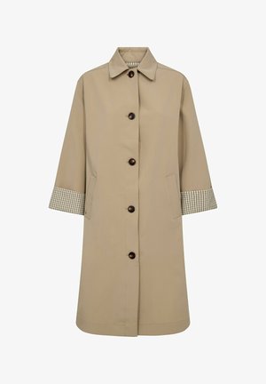 Bež dolg plašč s klasičnim ovratnikom, črnimi gumbi spredaj, stranskimi žepi in karo notranjimi manšetami, ki so vidne na zavihanih rokavih.