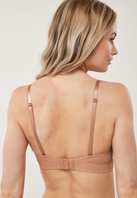 Biustonosz w kolorze cielistym o gładkiej, satynowej fakturze, z cienkimi regulowanymi ramiączkami i zapięciem na haftki z tyłu.