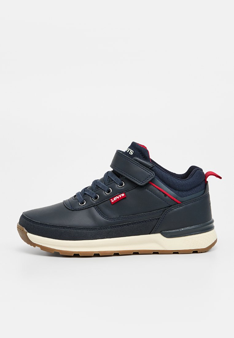 Zapatillas azul marino con acabado de cuero suave, acentos de tela, detalles en rojo y una correa de velcro sobre el sistema tradicional de cordones.