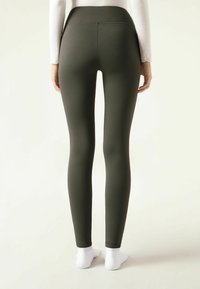 Olivgrüne Leggings mit hohem Bund, gefertigt aus einem glatten, dehnbaren Material. Die Unterseite der Leggings hat einen schlichten Saum.