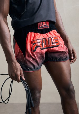 Red and black athletic shorts with a glossy logo and intricate patterns. Made of lightweight material, featuring a drawstring waistband.