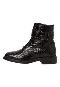 Bottine noire avec un motif crocodile en relief et brillant. Elle possède un laçage sur le devant, une boucle sur le côté et un petit talon.