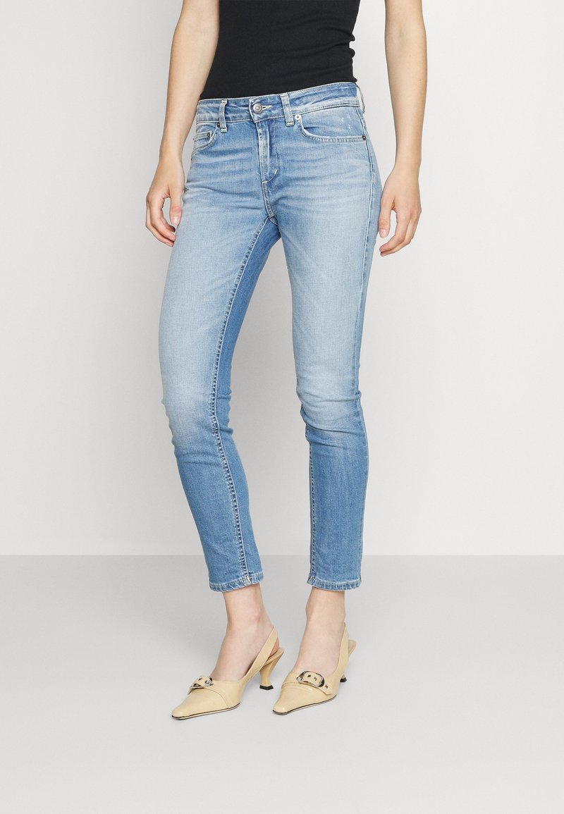 Ljust blå denimjeans med slim fit, medelhög midja och blekt mönster. Kombinerat med gula klackskor med spänne.