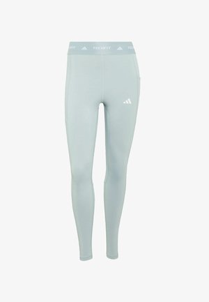 Lichtblauwe leggings gemaakt van een glad, rekbaar materiaal. Voorzien van een brede tailleband met het "TECHFIT" logo en een klein Adidas-logo aan de zijkant.