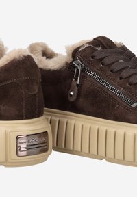 Braune Wildleder-Sneaker mit beiger Gummisohle und Plattform. Zu den Merkmalen gehören ein Futter aus Kunstfell, Schnürsenkel und ein seitlicher Reißverschluss mit metallischen Akzenten.