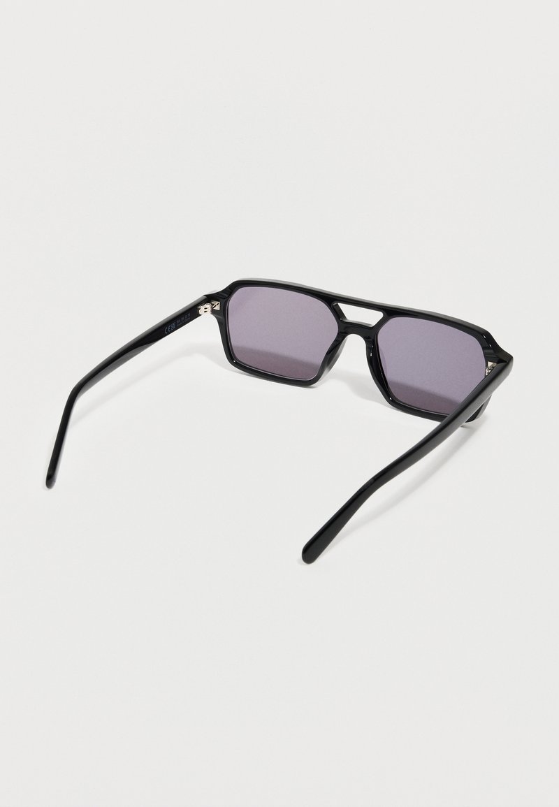 Black rectangular sunglasses with purple tinted lenses and a double bridge, resting open on a white surface.