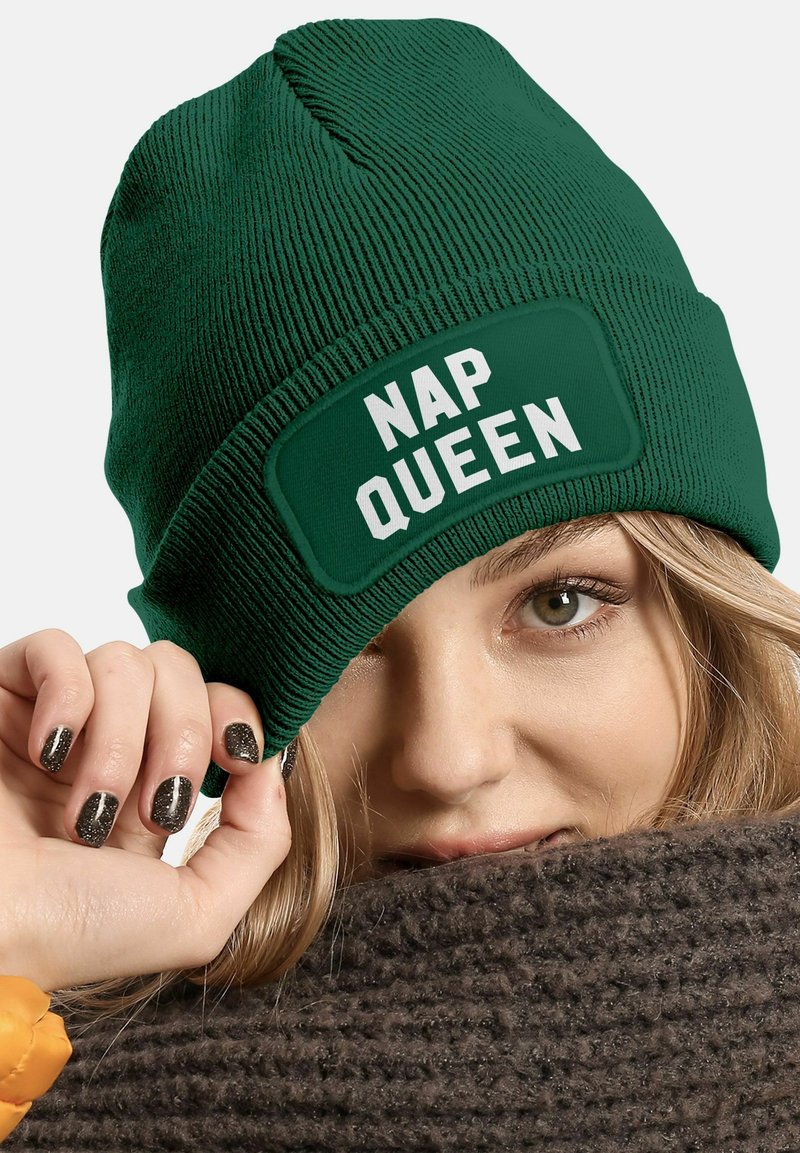 Green knitted beanie with a textured surface and a rectangular patch reading "NAP QUEEN" in bold white letters.