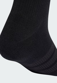 Čierna ponožka s rebrovanou textúrou, ktorá má hladkú časť na špičke a jemné prúžkované detaily na hornej časti. Materiál pôsobí pružne a flexibilne.