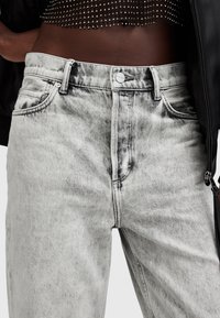 Jeans de mezclilla gris descolorido con cintura alta, dos bolsillos frontales y cierre de botón metálico. Presentan un sutil desgaste para dar textura.