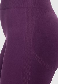 Leggings viola con pannelli testurizzati e traspiranti e un alto elastico per supporto. Il tessuto ha una finitura liscia e una buona elasticità.