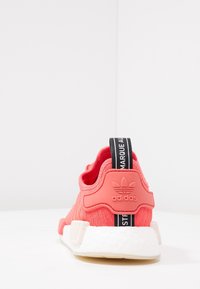 Korálové sportovní boty s pleteným svrškem, textura akcenty, bílá mezipodešev a černá poutko s logem "adidas".