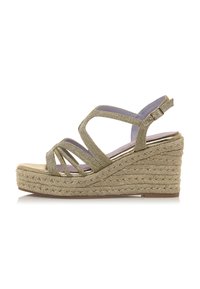 Sandale wedge en espadrille dorée avec des sangles entrecroisées, une finition métallique, une semelle en jute tissé et une semelle intérieure rembourrée. Fermeture à boucle au niveau de la cheville.