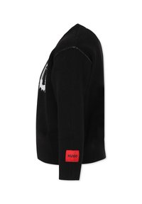 Maglione lavorato a maglia nero con scollatura rotonda, maniche lunghe e un'etichetta rossa con la scritta "HUGO" sul polsino sinistro. Texture liscia.
