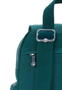 Zaino in tessuto teal con una trama texturizzata, caratterizzato da un accento in metallo argento e una tasca con zip sul lato per riporre oggetti.