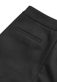 Schwarze Stoffhosen mit glatter Textur und einer versteckten Gesäßtasche. Der Bund ist strukturiert und der Stoff wirkt langlebig.