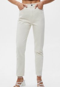 Jeans de mezclilla de talle alto, color blanco roto, con un diseño de pierna recta, que cuentan con bolsillos estándar y un cierre de botón metálico.