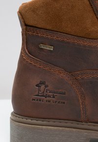Rudonos odinės botai su zomšiniais elementais, GORE-TEX etiketė, siuvinėti akcentai ir įspaustas Panama Jack logotipas. Patiestu paviršiumi ir tvirtu dizainu.