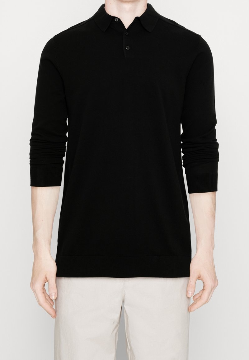 Schwarzes Poloshirt mit langen Ärmeln, klassischem Kragen, drei Knöpfen, gerippten Bündchen und Saum, gefertigt aus weich strukturiertem Stoff.